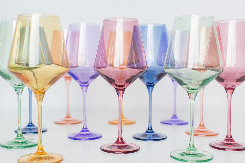 A row of elegant wine glasses in various iridescent pastel colors, reflecting light.