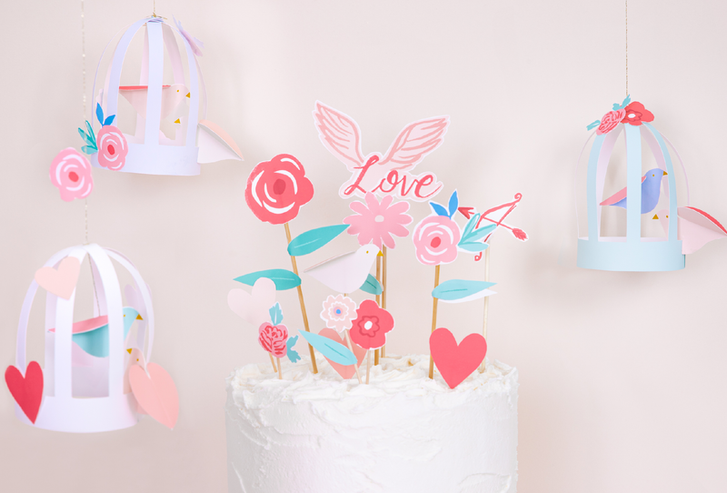 Pastel paper birdcages with flowers decorate a cake table for a Valentine craft display