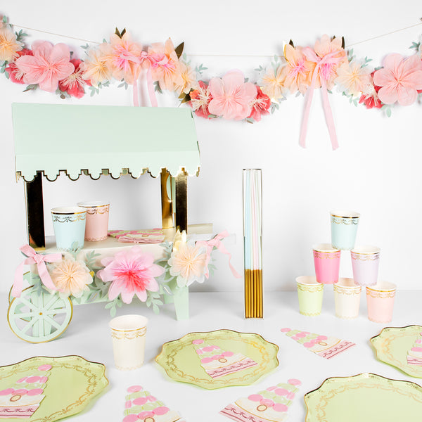 Beautiful pastel plates, cups, napkins, floral garland, and a centerpiece to display macarons.