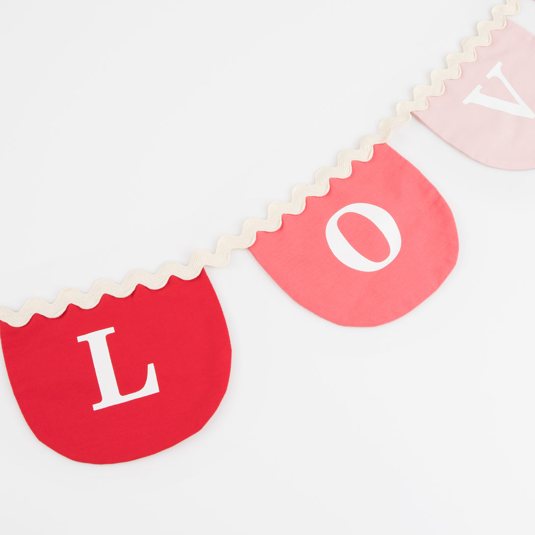 Our Valentine's decoration, a fabric garland, has scalloped pennants in red and pink with a romantic message.