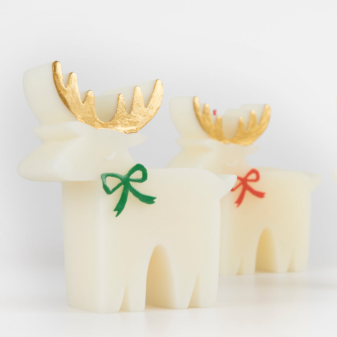 These Christmas table candles are reindeers with on-trend bows, gold details and fabulous colored wicks, a great host gift.