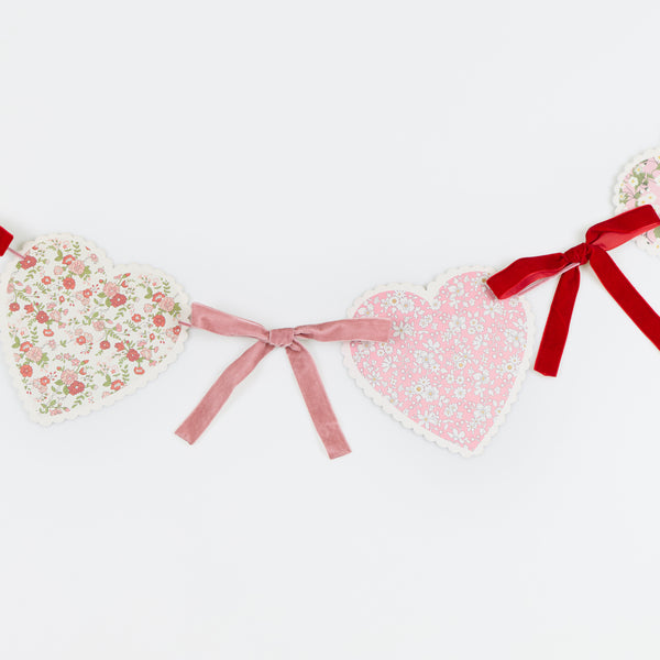 Our Valentine's Day garland feature paper hearts with floral Liberty print designs and pink and red luxe velvet bows. Image2