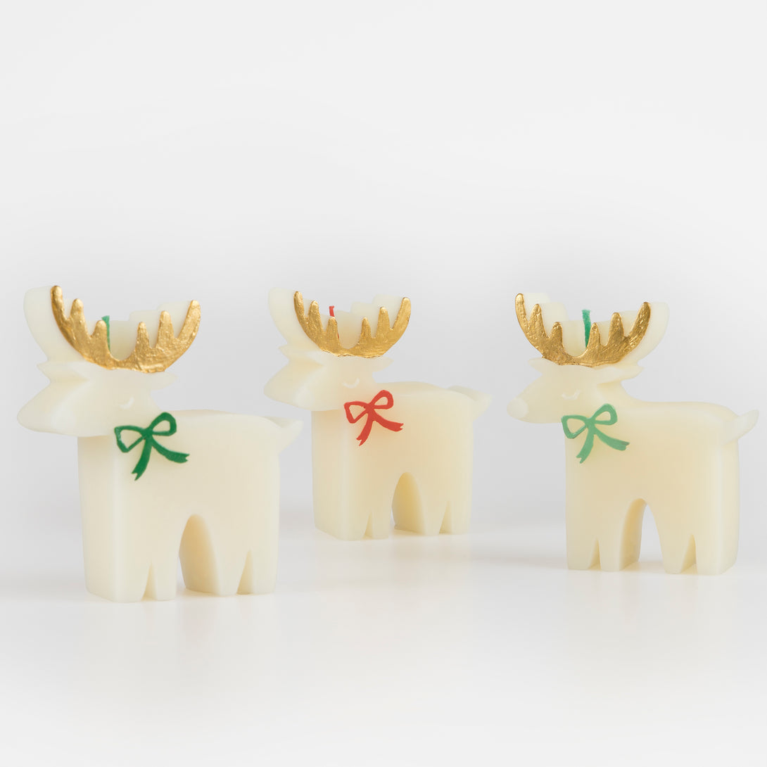 These Christmas table candles are reindeers with on-trend bows, gold details and fabulous colored wicks, a great host gift.