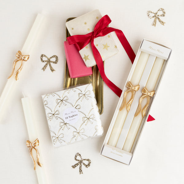 Our golden Christmas host gift set includes two table candles, with gold stripy bow details, and a pack of paper napkins with gold bow designs. Image2