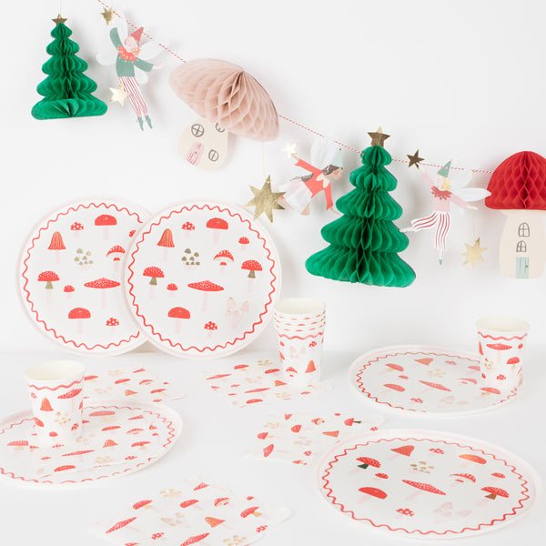 Our special Christmas party supplies include mushrooms and fairy designs on party plates, party napkins and cups, and a festive garland.