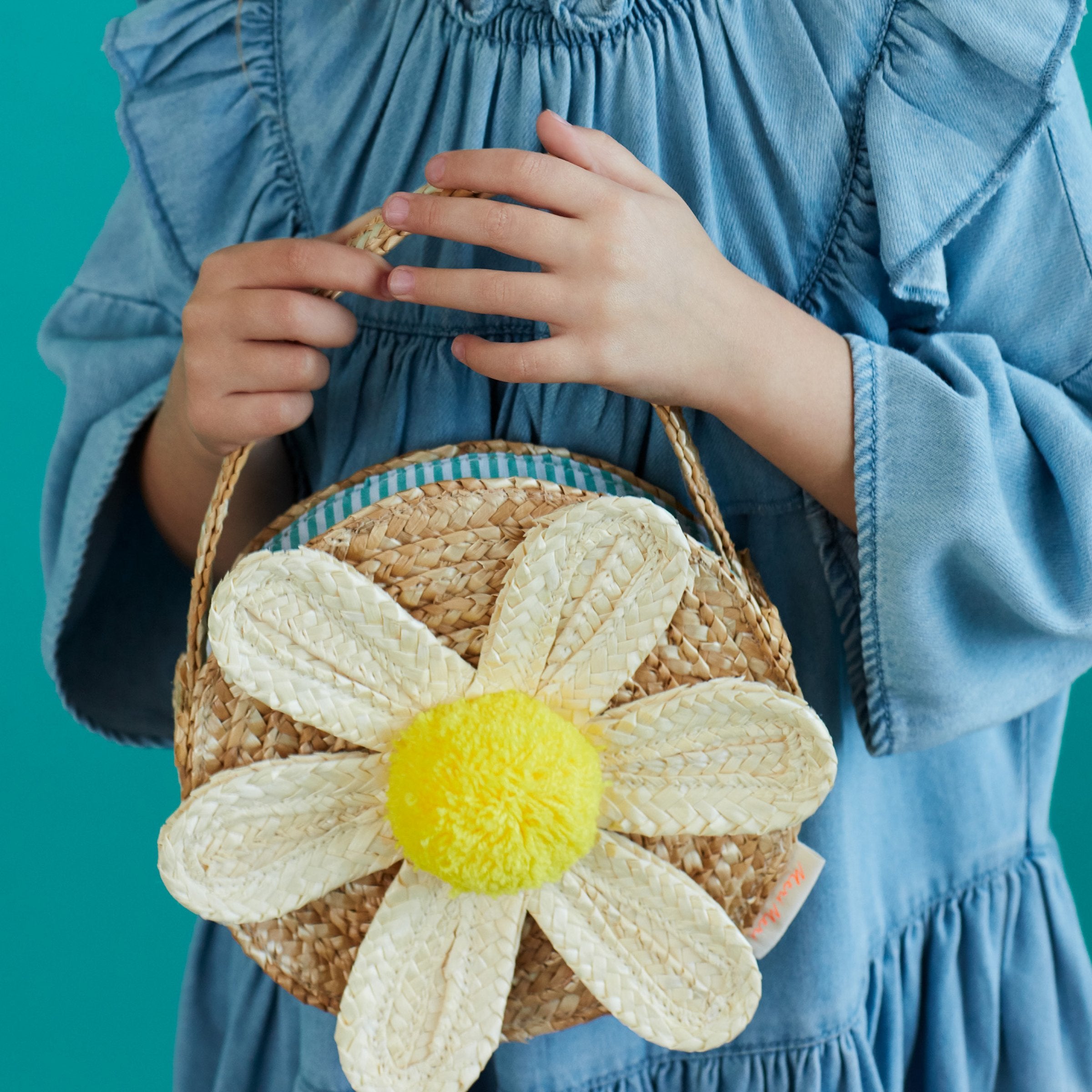This sensational straw kids bag has a raffia daisy with a yellow pompom in the center.