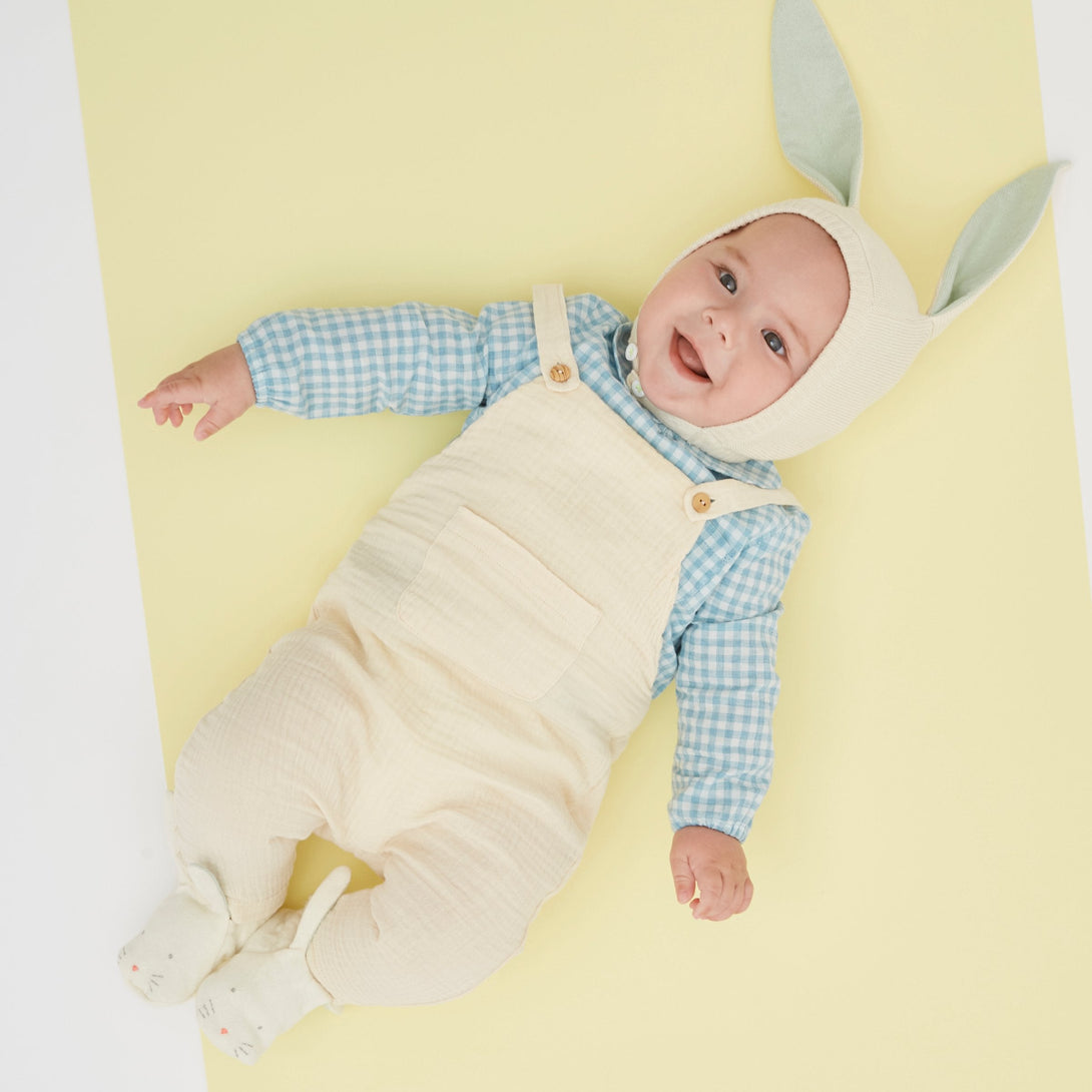 This delightful bunny baby bonnet is crafted from knitted organic cotton, with mint detail on the ears, and fastens with ivory colored buttons.