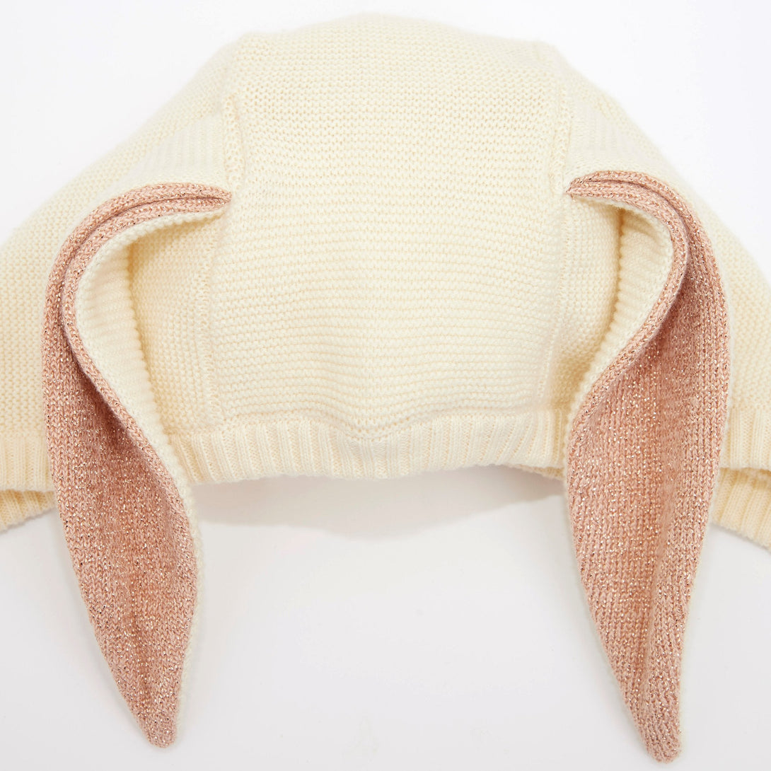 This organic cotton bunny bonnet has a shimmering peach inner on the ears, and an ivory colored button fastening.