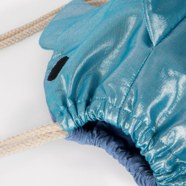 This shiny shark is  a backpack crafted from blue lamé fabric with a cotton lining and cord straps. Image5