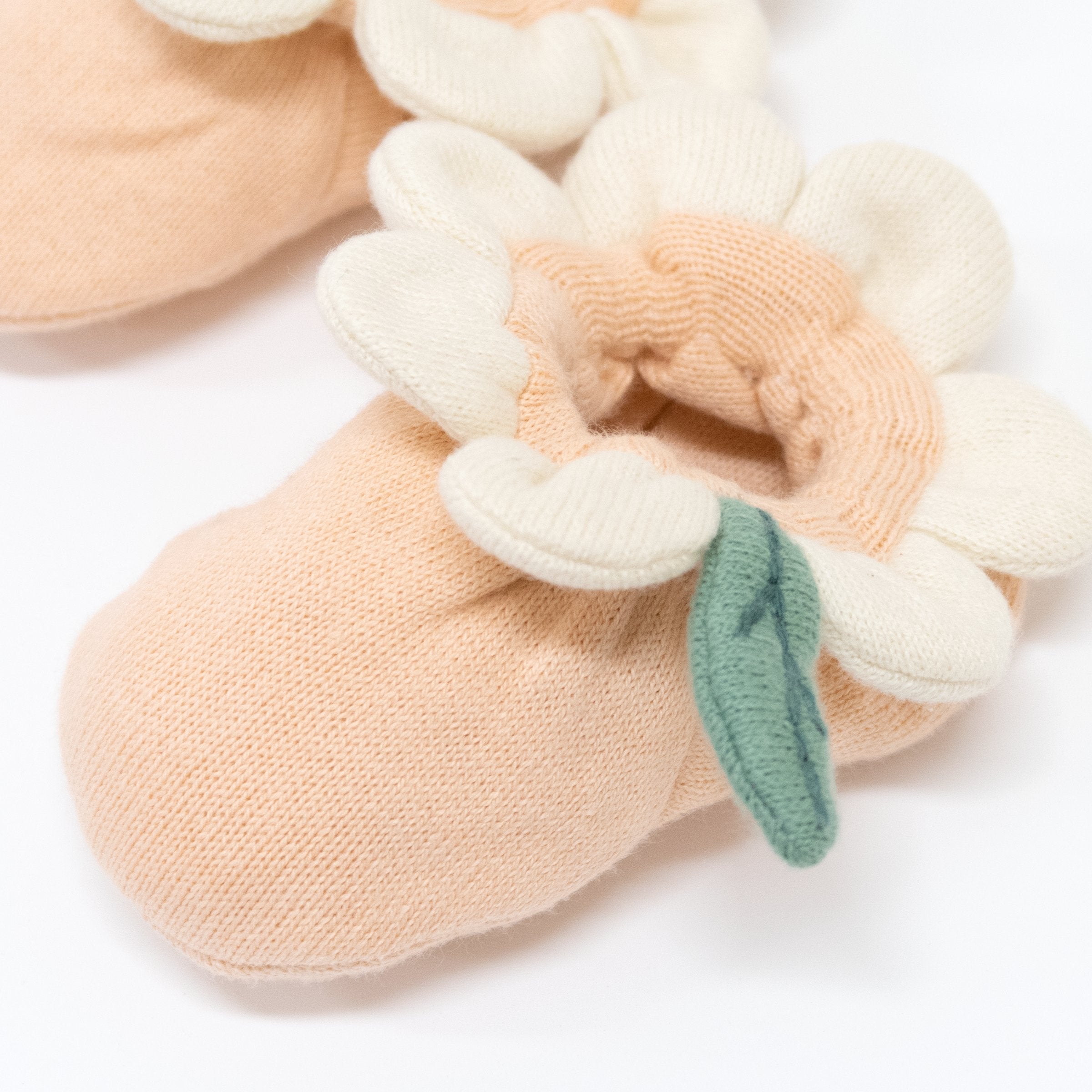 These peach daisy baby booties are crafted from knitted organic cotton, with a peach inner, and cream petal and green leaf detail.