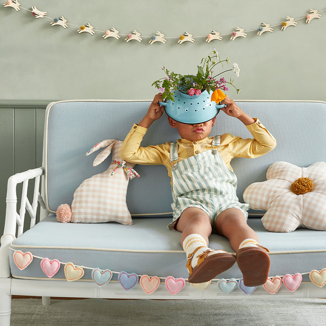 This decorative gingham print cushion is crafted in the shape of a daisy with a fun pompom center.