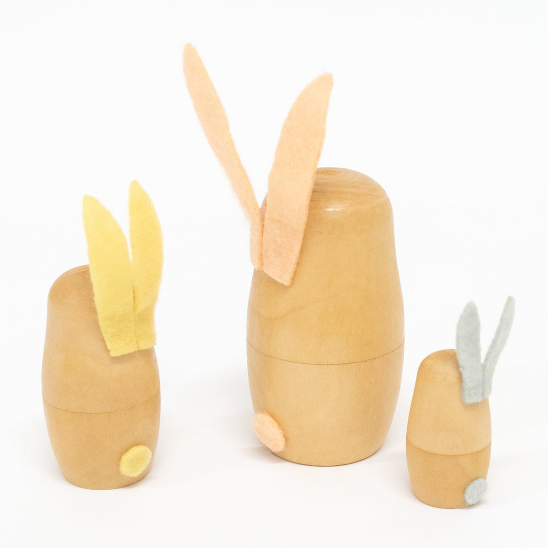 These stacking bunnies are crafted from wood, with gold features, and felt ears and tails.