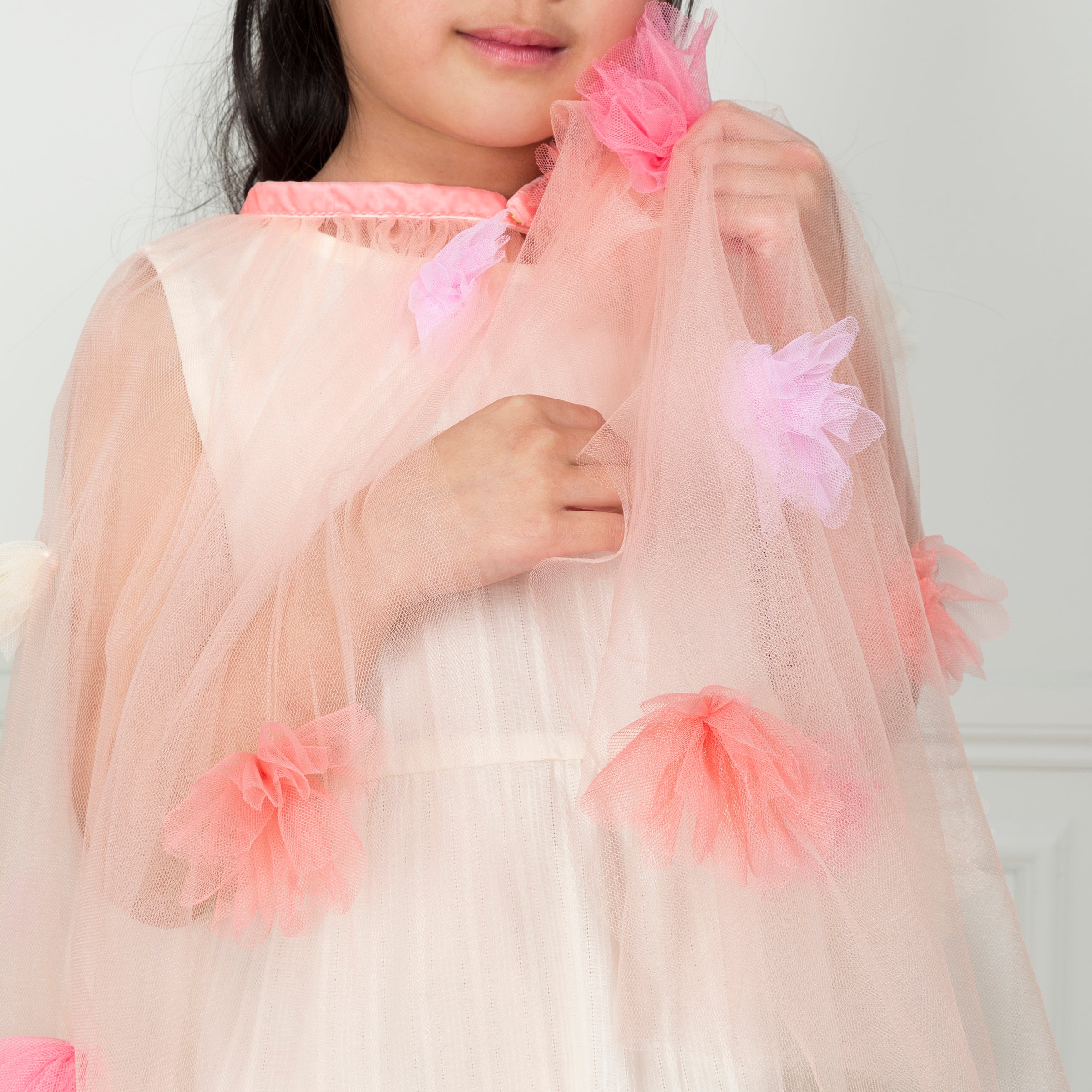 Our kids cape is crafted from tulle with tulle flower embellishments.